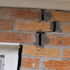 A brick wall displaying stair-step cracks and messy tuckpointing on a Overland Park home